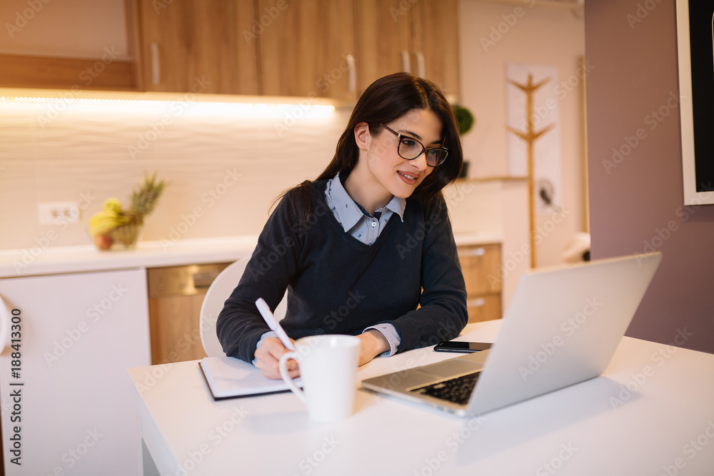 Pretty brunette working from home and writing notes.