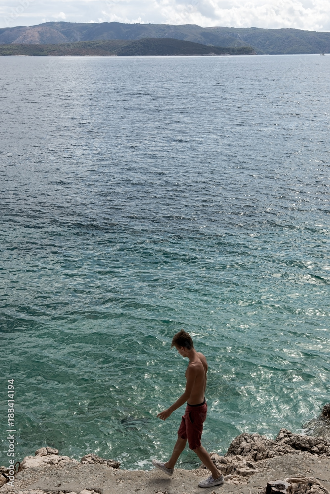 The top view of the young boy runs along the stony bank of the Adriatic Sea