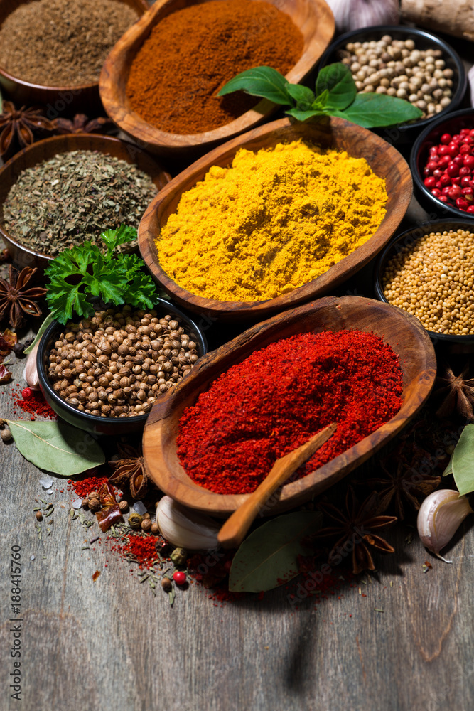 Fototapeta premium assortment of various spices and herbs on a wooden background, vertical closeup