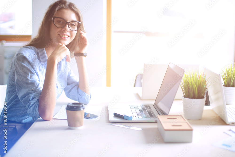 Obraz premium Young woman sitting in office table, looking at laptop computer screen . Young woman