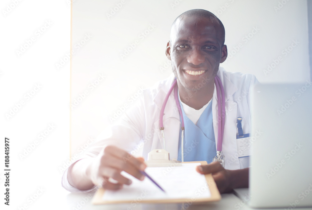Portrait of young male doctor wearing headset while using computer at desk in clinic. Doctor. Portrait of young male doctor wearing headset while using computer at desk in clinic. Doctor.