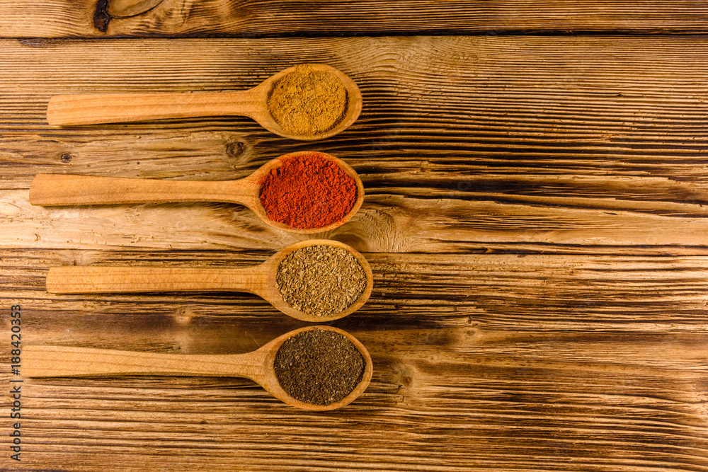 Spoons with the different spices on wooden table. Top view Spoons with the different spices on wooden table. Top view