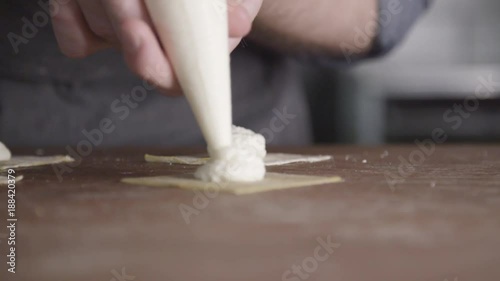 Chef squirts filling into ravioli dough, close up