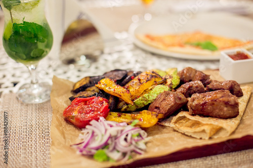 Meat and a variety of grilled vegetables on a wooden board