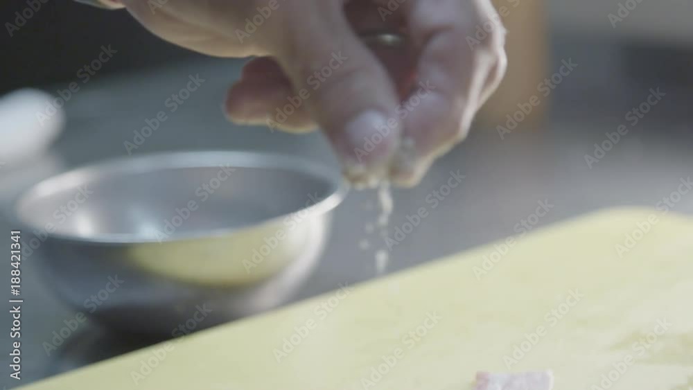 Chef adds seasoning, close up Chef adds seasoning, close up