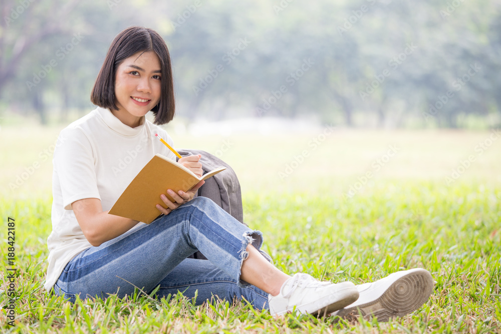 Asian Woman sketch picture on book with attractive smiling at garden. People lifestyle concept.