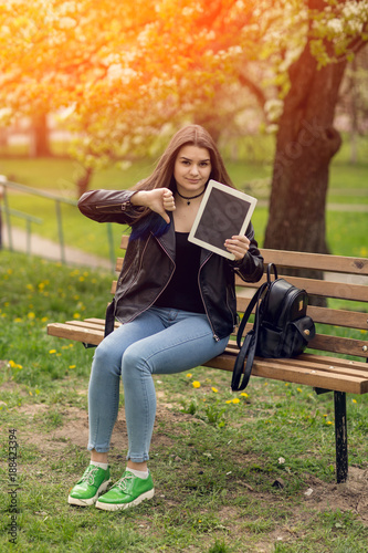 Young girl in the park with a tablet in hand.