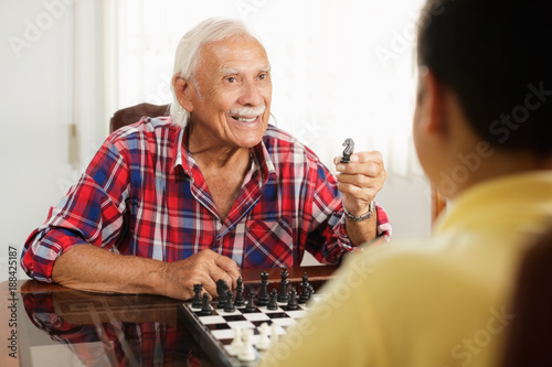 Grandpa Playing Chess Board Game With Grandson At Home