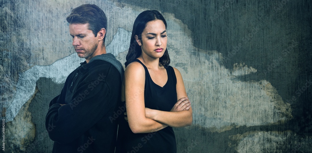 Composite image of sad couple with arms crossed standing back to