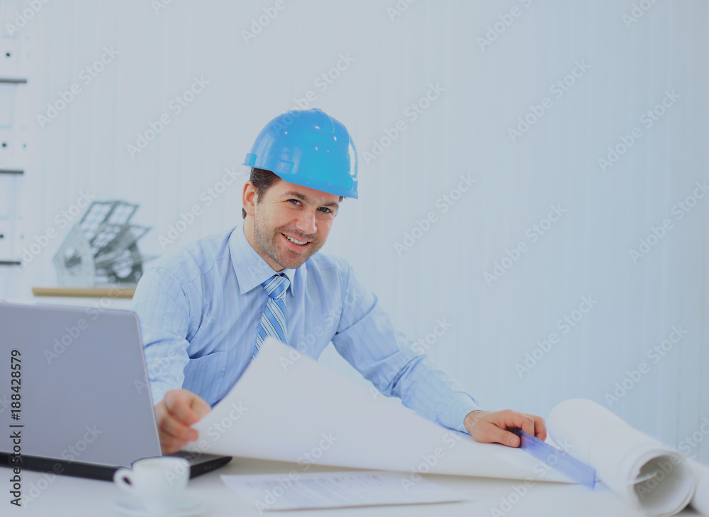 Architect looking working in office at desk. Wearing hardhat and taking notes on paper. Architect looking working in office at desk. Wearing hardhat and taking notes on paper.
