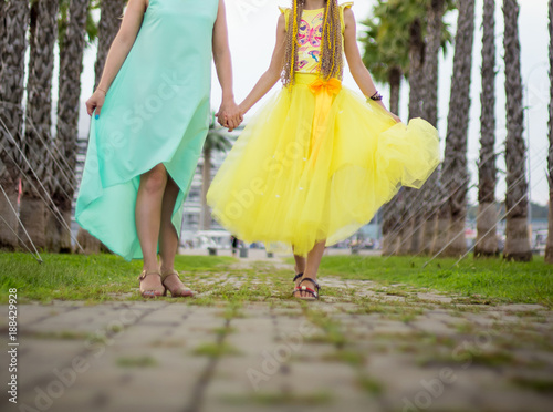 Mother and daughter are walking in the park among the palms