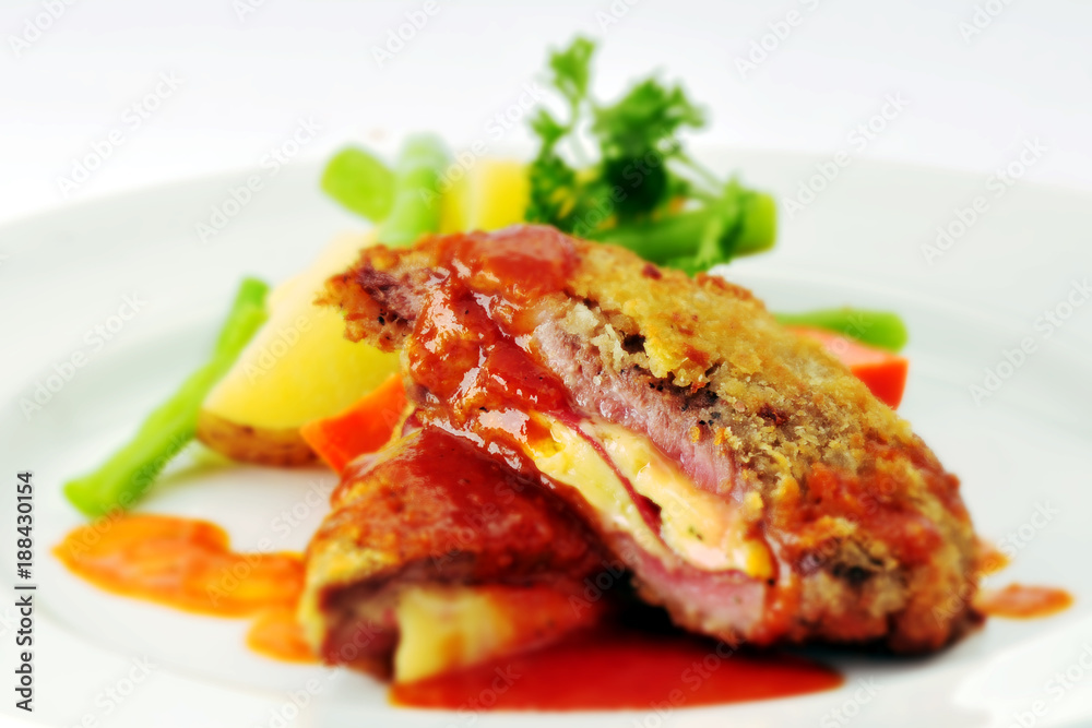Traditional Austrian Wiener Schnitzel with vegetables on plate, isolated on white background.