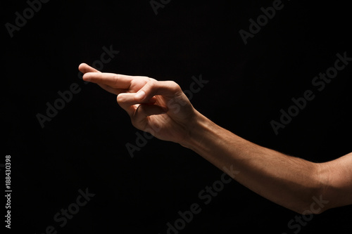 Male hand crossed fingers for luck isolated on black