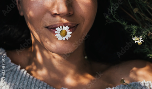 Obraz na plátně Cropped close-up horizontal shot of brunette young girl with daisy flower in mouth outdoors enjoying nature