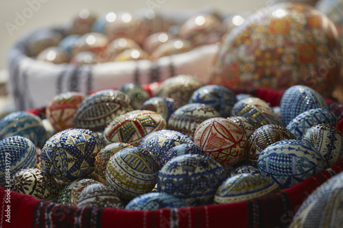 Pile of colorful manually crafted, painted decorative Easter eggs in a basket. Closeup, shallow depth of field, selective focus.