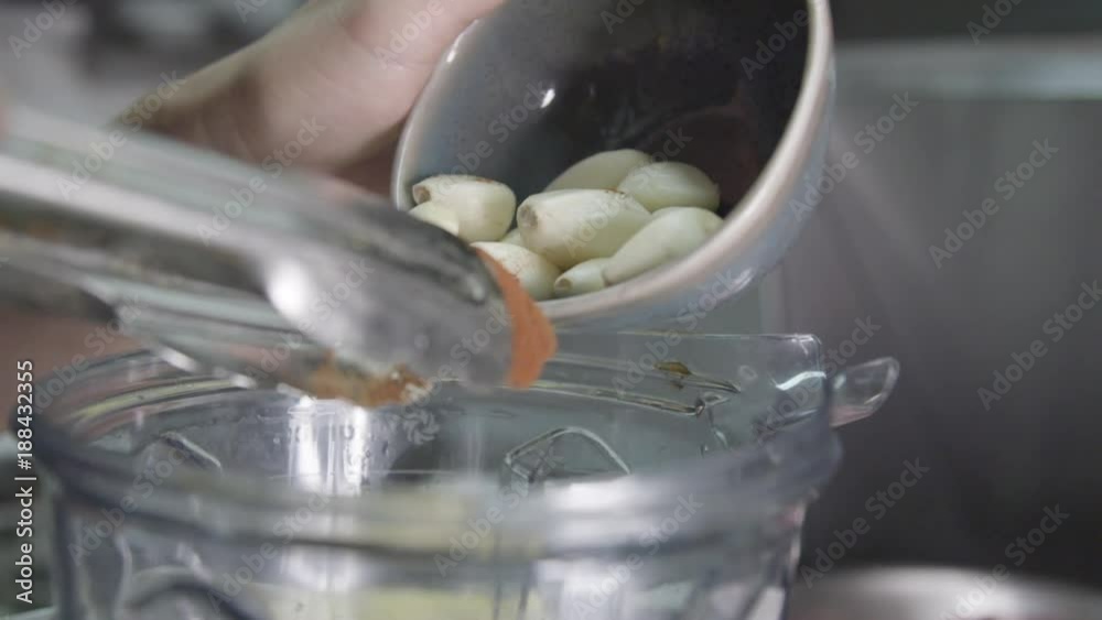 Chef dumps cloves of garlic into blender, slow motion Chef dumps cloves of garlic into blender, slow motion