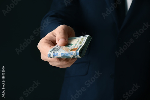 Businessman holding bribe on black background