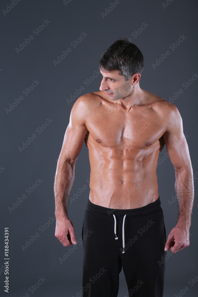 Fototapeta premium muscular man. Muscular man on a grey background showing muscles. Fitness instructor. Fitness professional. Workout. Men's fitness.