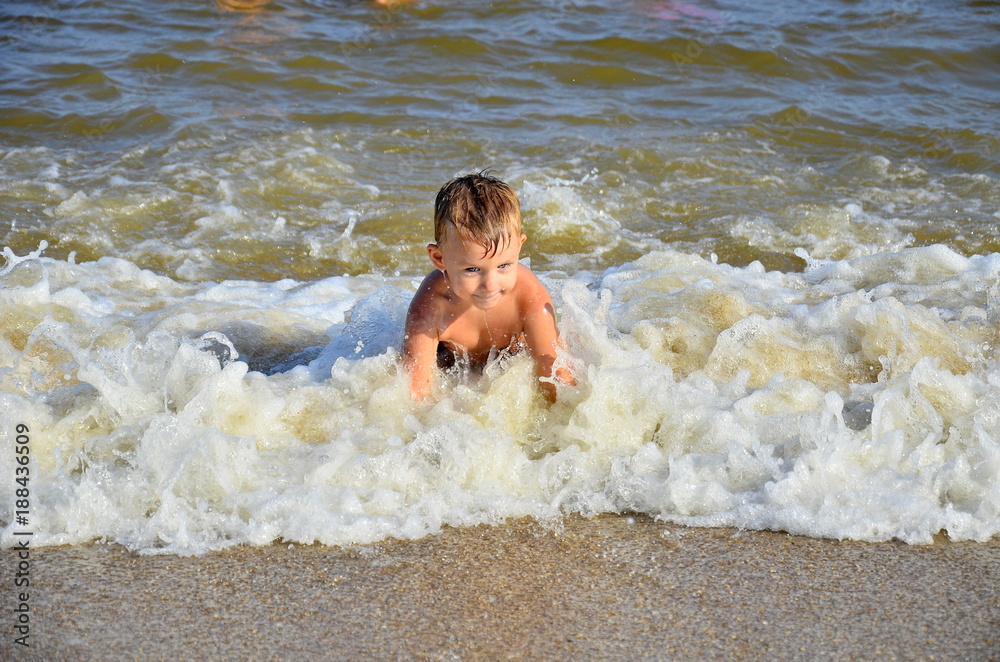 Adorable little blond kid boy having fun on ocean beach. Excited child playing with waves, swimming, splashing and happy about family vacations in Miami, Florida, USA. Adorable little blond kid boy having fun on ocean beach. Excited child playing with waves, swimming, splashing and happy about family vacations in Miami, Florida, USA.