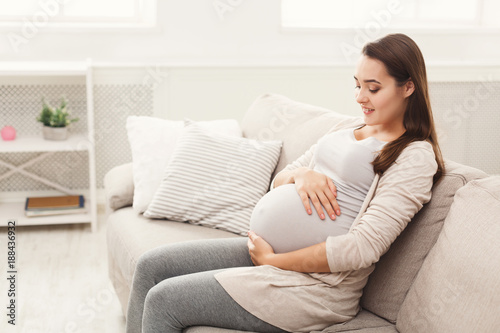 Pregnant woman caressing her belly at home