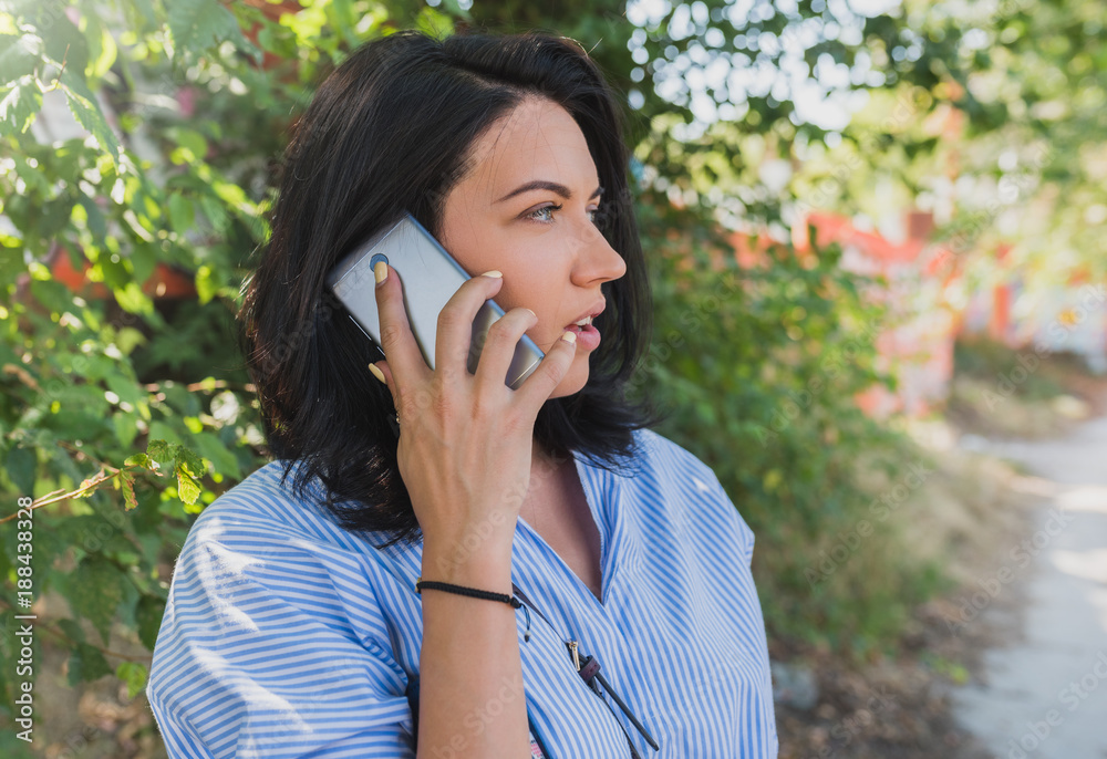 Cheerful young Caucasian woman wearing blue shirt talking on mobile phone about new project. People, lifestyle and business concept. Cheerful young Caucasian woman wearing blue shirt talking on mobile phone about new project. People, lifestyle and business concept.