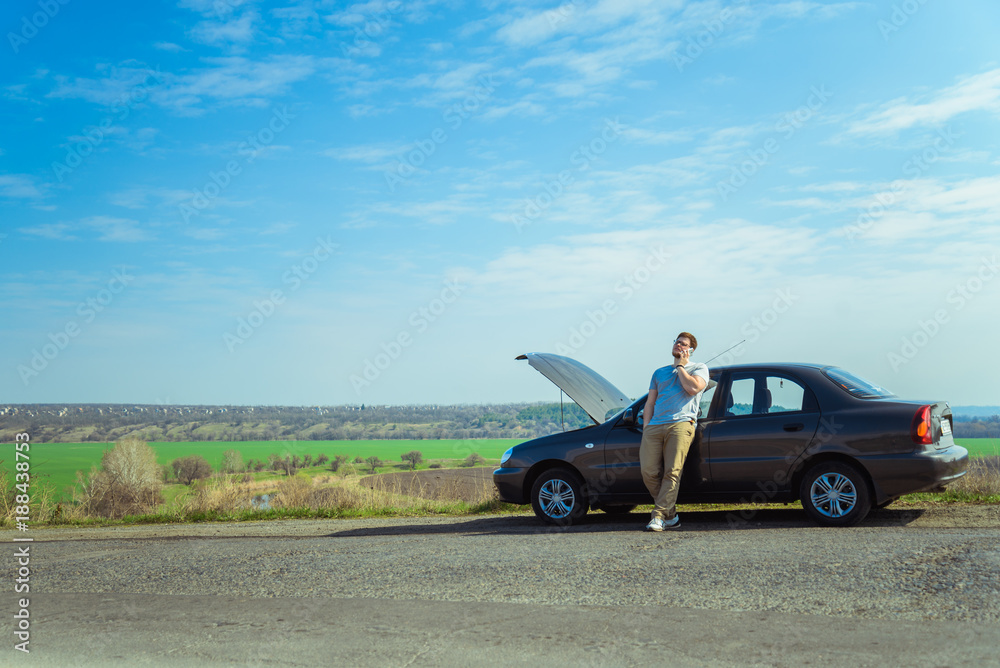 young man stands near broken car young man stands near broken car