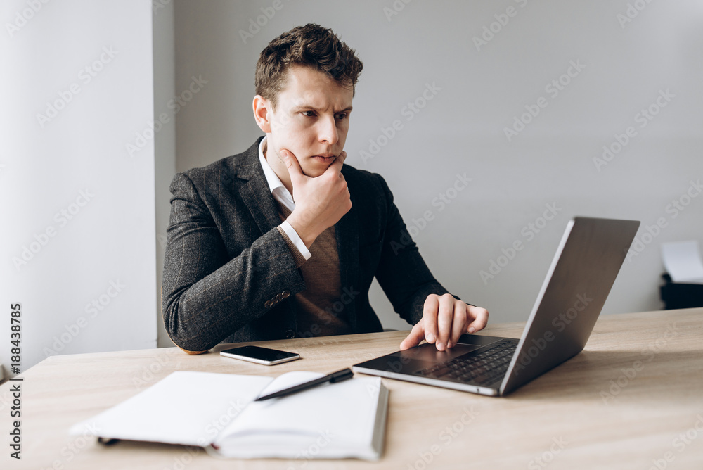 Image on which a concentrated serious businessman is working on laptop in his office Image on which a concentrated serious businessman is working on laptop in his office