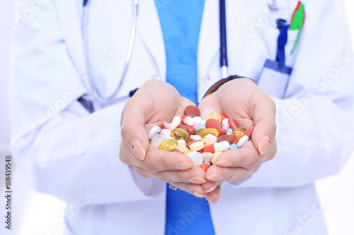 Doctor holding heap of drugs in a hand. Woman doctor