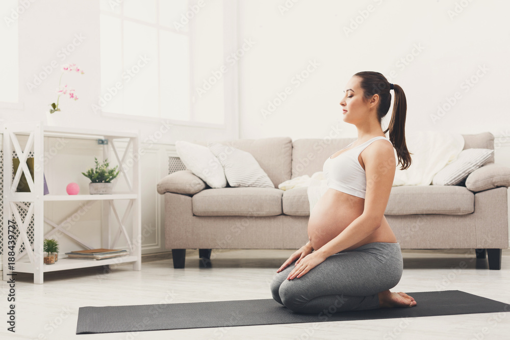 Happy pregnant woman training yoga in hero pose Happy pregnant woman training yoga in hero pose