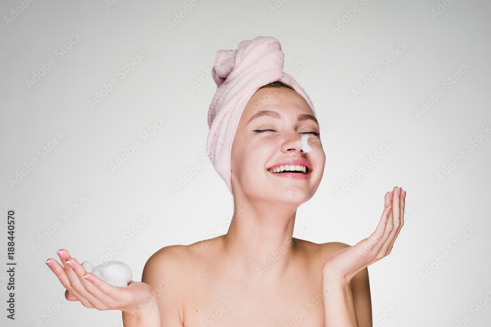 happy laughing girl with pink towel on head applying cleansing foam on face happy laughing girl with pink towel on head applying cleansing foam on face