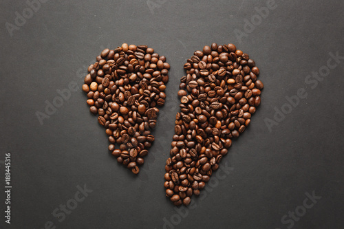 Brown coffee beans in form of broken heart isolated on black texture background for design. Saint Valentine's Day card on fabruary 14, holiday concept.