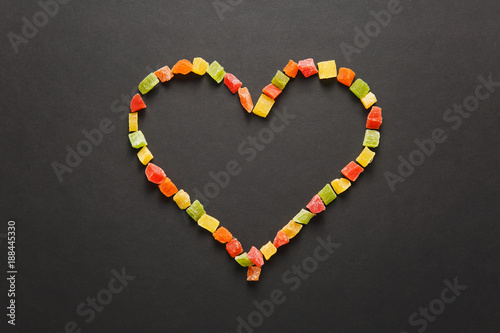 Candied fruits in the form of heart isolated on black background for design. Saint Valentine's Day card on fabruary 14, holiday concept.