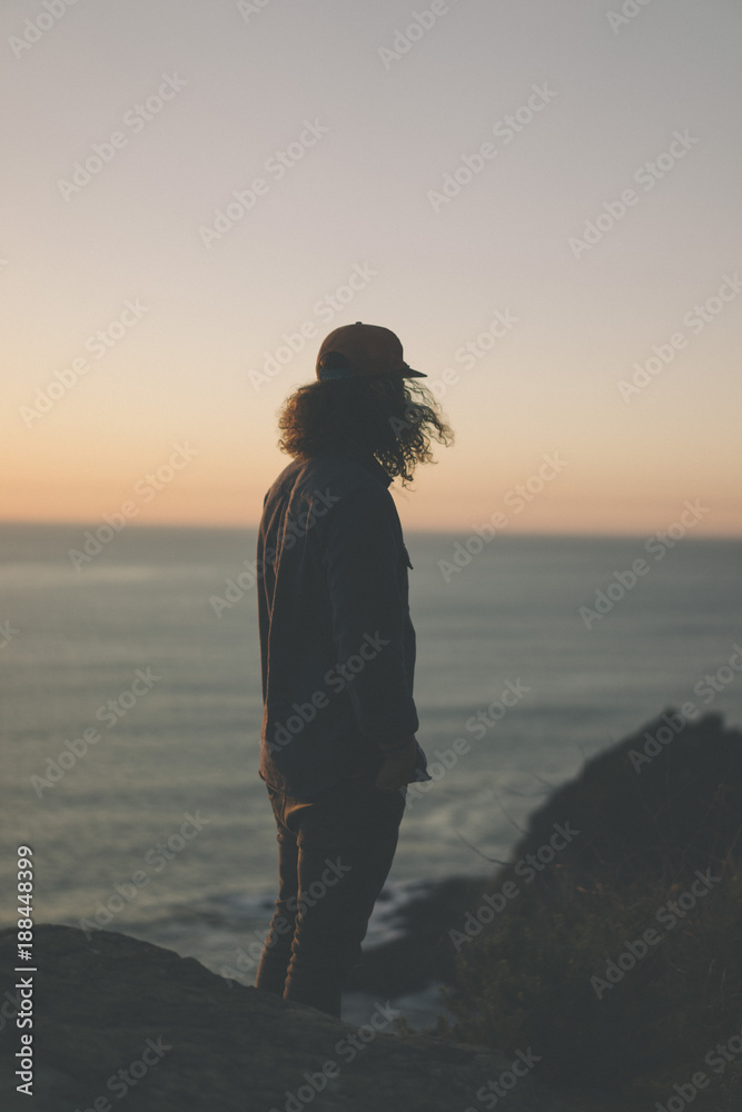 Side view of man standing on the beach and looking sunset view Side view of man standing on the beach and looking sunset view