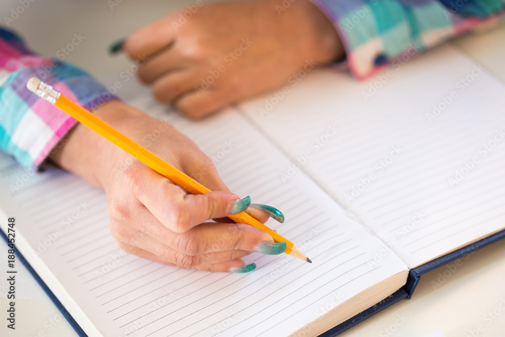 Female hand writing on paper with a pencil closeup