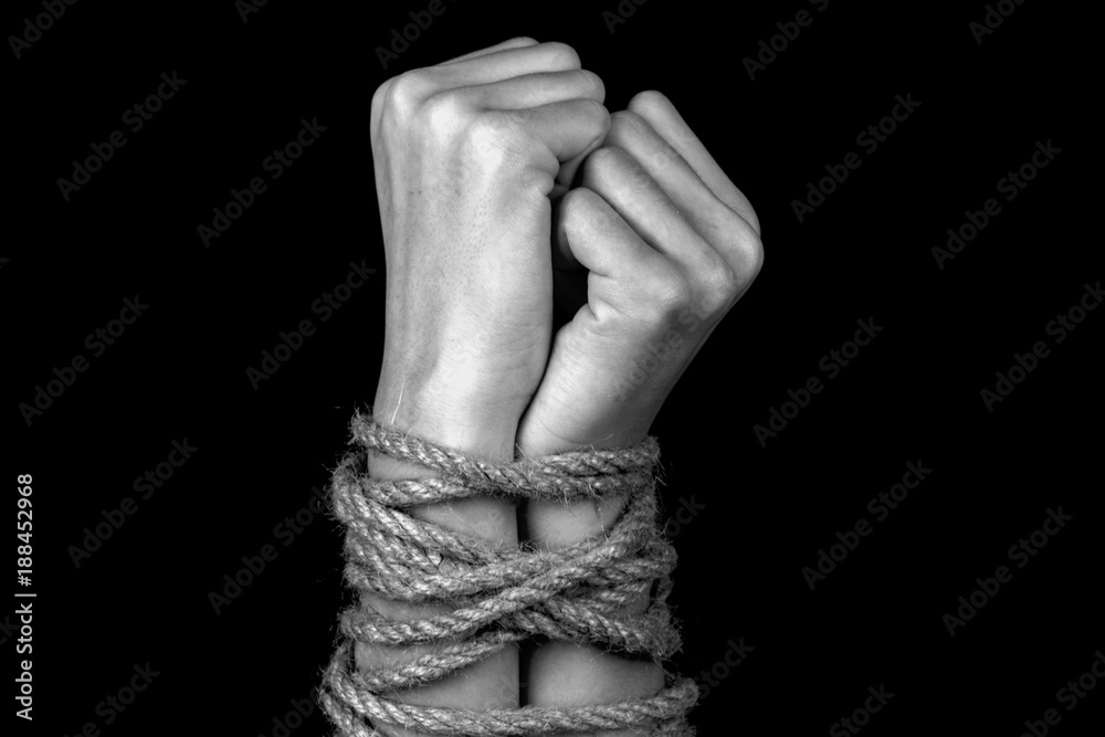 hands tied with a rope close-up black background monochrome Stock