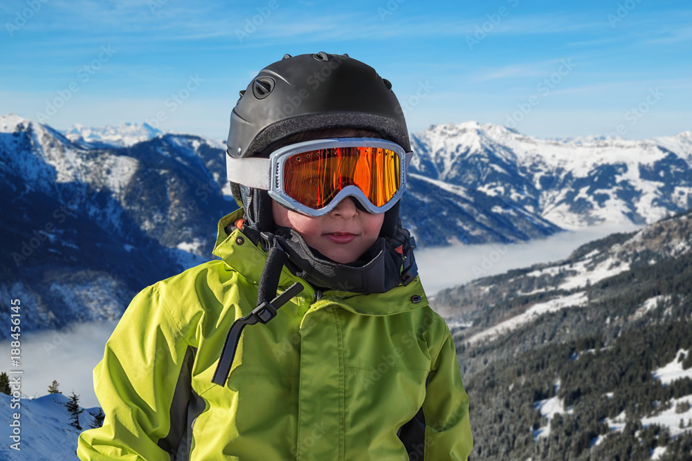 Portrait of boy in helmet and ski goggles on a sunny day in the mountains. Active outdoor childhood concept