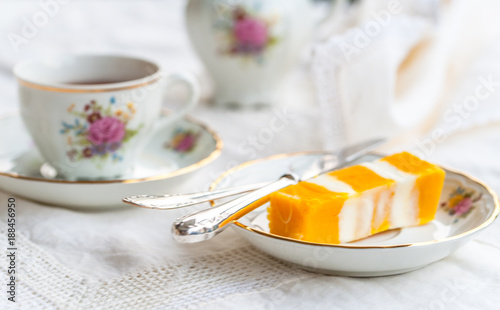 colorful yellow-and-white piece of cake on a porcelain dish with siverware