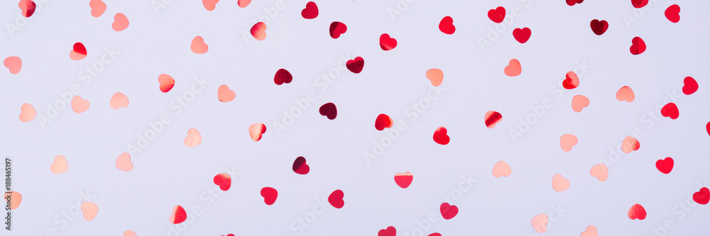 Grey background with red glitter heart confetti. Valentine day concept. Trendy minimalistic flat lay design background