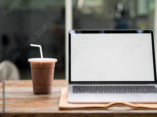 Laptop on wooden desk with iced coffee in the cafe.