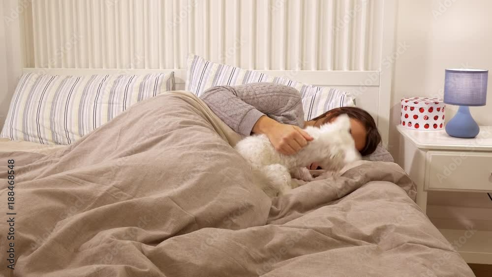 Happy beautiful woman cuddling and sleeping in bed with puppy dog Happy beautiful woman cuddling and sleeping in bed with puppy dog