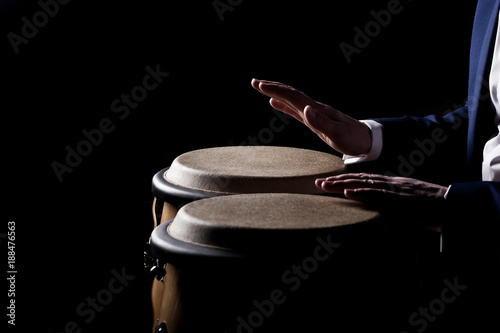 Canvas Print Hands of a musician playing on bongs in dark tones
