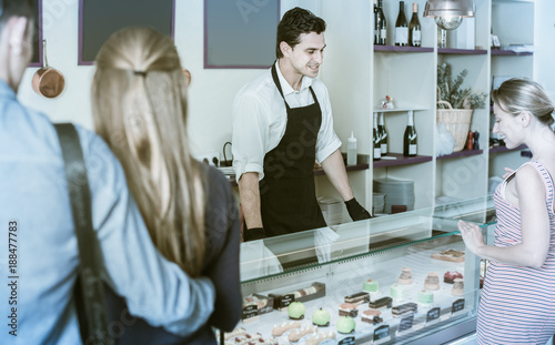 Smiling man confectioner serving visitors in cafe photo