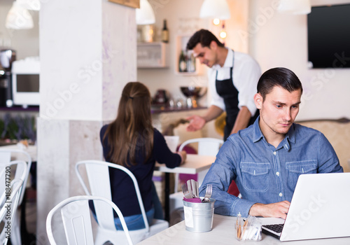 young man using laptop in modern cafe
