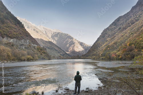 A man wearing a green sweater standing in the valley looked down at the scenery © clearjade