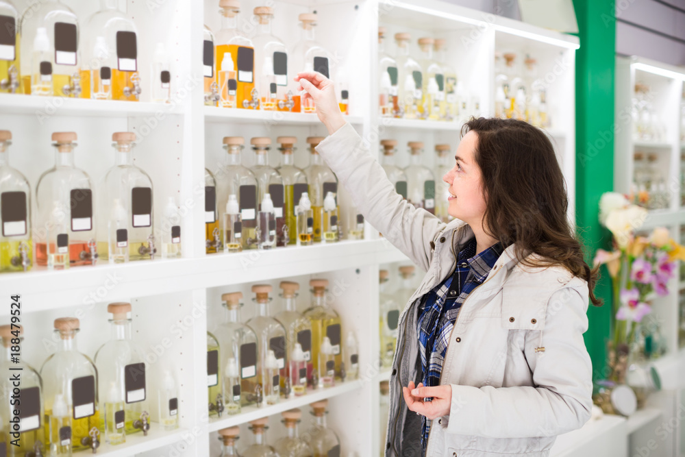 Girl buying perfume in fragrance boutique. - obrazy, fototapety, plakaty 