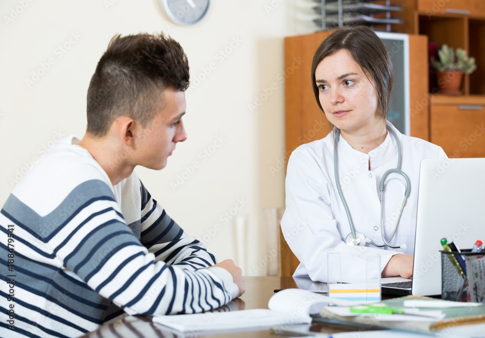 Female doctor questioning teen patient at office