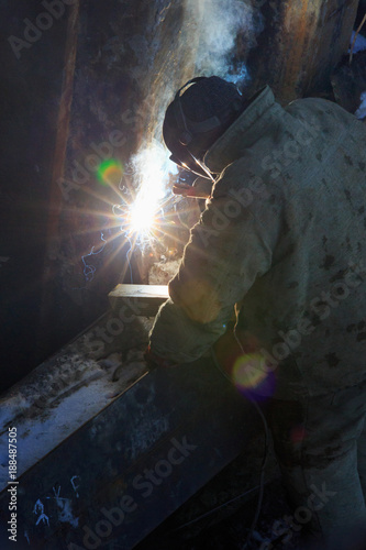 Welder from the back, in backlight from electric welding. © Sergej