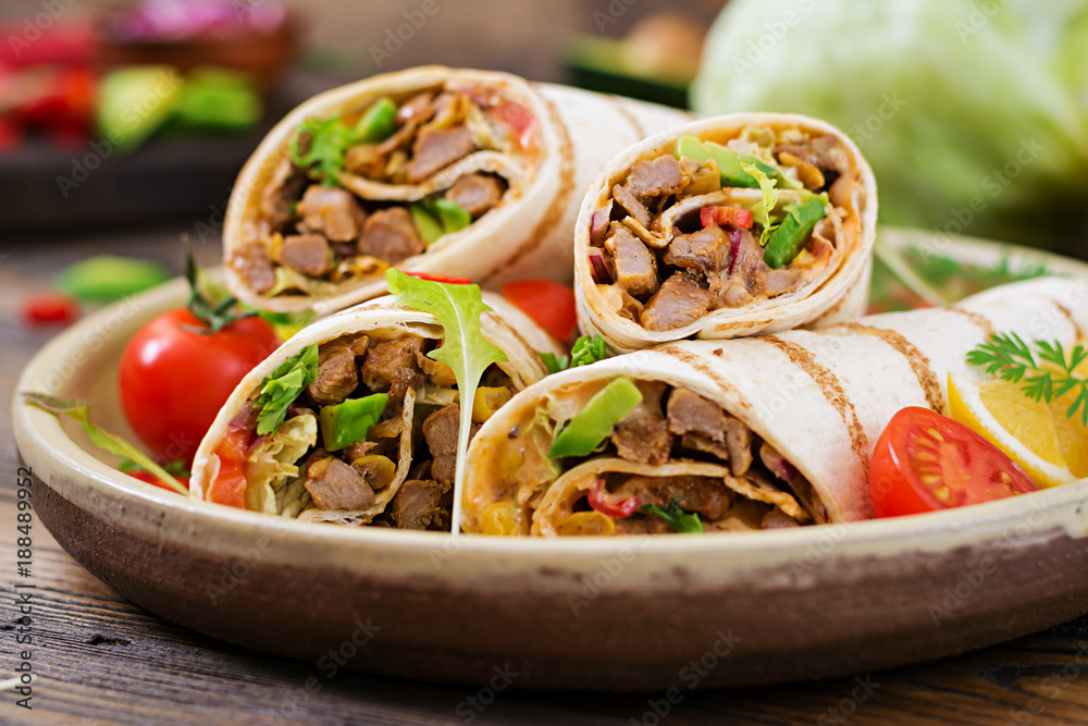 Burritos wraps with beef and vegetables on a wooden background. Beef burrito , mexican food. Healthy food background. Mexican cuisine. Burritos wraps with beef and vegetables on a wooden background. Beef burrito , mexican food. Healthy food background. Mexican cuisine.