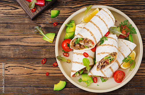 Burritos wraps with beef and vegetables on a wooden background. Beef burrito , mexican food. Healthy food background. Mexican cuisine.Top view.