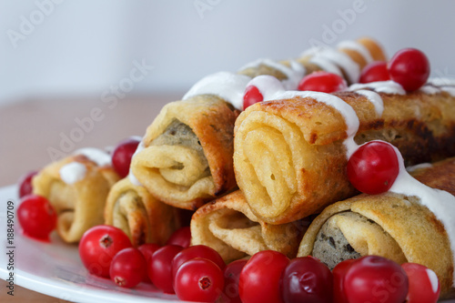 Traditional sweet rolled pancakes with poppy seeds on the plate closeup
